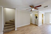 Located at 2501 Whitney Lawn Dr in Metairie, Louisiana, this two-story, two-bedroom, three-bathroom home offers a well-organized layout spread evenly across two floors. The main level features an open living area with light hardwood-style flooring, crown molding, and a ceiling fan that adds to the airy feel of the space. Natural light filters in through a window at the far end of the living room, creating a bright and welcoming atmosphere. Adjacent to the living area, the galley-style kitchen is equipped with light-toned cabinetry, a double-basin stainless steel sink, a dishwasher, an electric range, and a refrigerator — all set atop matching hardwood-style flooring. A bathroom on this level features clean white fixtures, a vanity with mirror, and a tiled shower. Carpeted stairs lead to the upper floor, where both bedrooms are located. The primary bedroom offers generous proportions, ceiling fan, crown molding, and the convenience of two closets. The second bedroom is similarly appointed with carpet flooring, a ceiling fan, crown molding, and a window providing natural light. A stylishly appointed bathroom upstairs features dual mirrors, sconce lighting, and a clean white vanity. Throughout the home, consistent finishes and neutral tones create a cohesive and comfortable living environment.