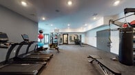 Located at 177 Blue Hills Drive in Nashville, TN, this fitness center offers a generously sized, single-floor workout space designed to accommodate a wide range of exercise routines. The facility features a clean, modern aesthetic with white and gray walls, recessed lighting throughout, and durable rubber and carpet flooring suited for high-traffic use.

The cardio zone is well-equipped with a row of True-brand treadmills and additional cardio machines, positioned along the perimeter to maximize open floor space. A dedicated strength training area includes a multi-station cable machine, a full dumbbell rack ranging across various weights, adjustable weight benches, and a TRX suspension system. Exercise balls in multiple sizes are neatly stored on a rack, supporting flexibility and functional training needs.

Large wall-mounted mirrors in the strength area enhance the sense of space while allowing users to monitor their form. Multiple entry points, including glass-paneled and solid doors, provide convenient access throughout the facility. The open floor plan allows for ample movement between equipment zones, making the space practical for both individual and group use. Overall, the fitness center presents a functional and well-organized environment suited for comprehensive physical training.