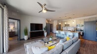 Located at 200–232 NW 135th Way in Newberry, Florida, this contemporary single-floor residence offers a thoughtfully designed open-concept layout with modern finishes throughout. The kitchen serves as a central hub of the home, featuring stainless steel appliances, white shaker cabinetry, a classic subway tile backsplash, granite countertops, and a spacious island with bar seating — all illuminated by stylish pendant lighting and a track lighting system. Wood-look flooring flows seamlessly from the kitchen into the expansive living area, which is anchored by a ceiling fan and opens directly to a private balcony through large sliding glass doors, allowing abundant natural light and outdoor views. The living space provides a comfortable, open atmosphere ideal for both relaxing and entertaining. Multiple well-appointed bedrooms are found throughout the unit, each featuring ceiling fans, wood-look flooring, and generous natural light from large windows. The primary suite includes an en suite bathroom with granite countertops, gray cabinetry, and a walk-in closet. Additional highlights include a dedicated in-unit laundry area. The consistent use of a cool gray, navy, and white palette with bold yellow accents gives the entire residence a cohesive and modern aesthetic.