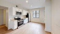 Located at 1030 East Genesee Street in Syracuse, NY, this well-appointed 4-bedroom, 3-bathroom unit offers a clean, modern aesthetic throughout its single-floor layout. Light wood-tone flooring flows seamlessly from room to room, complemented by crisp white walls and contemporary trim work that create a bright, cohesive atmosphere.

The kitchen is outfitted with stainless steel appliances — including a range, over-the-range microwave, dishwasher, and refrigerator — paired with white shaker-style cabinetry, light countertops, and a stainless steel sink. A window brings in natural light, making the kitchen feel open and functional.

The four bedrooms are generously sized, with the primary bedroom offering a notably spacious footprint. Each bedroom features the same light wood flooring and neutral walls, with windows providing natural light. Several bedrooms include built-in wall-mounted lighting and dedicated study areas.

Each of the three bathrooms is finished in a clean, modern style with white vanity cabinetry, undermount sinks, light countertops, and tub/shower combinations. One bathroom features large plantation shutters for natural light and privacy, while another includes a backlit vanity mirror and tile flooring. Two connecting hallways guide the layout efficiently, and four closets provide ample dedicated storage throughout the unit.