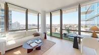 Located at 395 Carroll St in the Carroll Gardens neighborhood of Brooklyn, this thoughtfully designed two-bedroom, one-bathroom residence offers a refined urban living experience. Light hardwood flooring flows throughout, complementing the clean, contemporary aesthetic of the open-concept layout. The combined kitchen and living area serves as the heart of the home, where floor-to-ceiling windows frame sweeping panoramic views of the Brooklyn skyline. The kitchen is outfitted with warm wood cabinetry, white upper cabinets, a stainless steel range and refrigerator, and ample counter space. A private balcony extends the living area outdoors, accessible through large glass doors. The primary bedroom benefits from expansive windows with city views, filling the space with natural light, while the second bedroom provides a comfortable and versatile retreat. A dedicated closet and in-unit laundry add practical convenience. The bathroom features stone-tiled flooring, a soaking tub with glass enclosure, a walnut vanity, and matte black fixtures, delivering a polished, spa-like finish. Recessed lighting and crisp white walls throughout maintain a bright, modern ambiance.