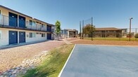 Located at 1950 North 43rd Avenue in Phoenix, Arizona, this single-level outdoor community space offers a well-rounded recreational environment designed for active living. At the heart of the grounds is a full-sized, paved basketball court with clearly marked lines and a regulation hoop, providing a dedicated area for sport and exercise. Adjacent to the court, a sand volleyball court with a net offers yet another option for group recreation.

The landscaping reflects a desert-adapted design, featuring a mix of manicured green lawns, decorative gravel beds, and river rock accents surrounding mature palm trees that lend a distinctly Southwestern character to the space. The grounds are dotted with tall, established palms that provide shade and visual interest throughout.

A covered pavilion structure sits toward the perimeter of the property, offering a shaded gathering area ideal for outdoor seating or community events. Exterior stairways connect to the adjacent two-story residential buildings, which feature open balconies and neutral stucco exteriors. The surrounding area benefits from abundant natural sunlight consistent with the Phoenix climate, and the expansive open layout contributes to a sense of openness and accessibility. Overall, the space is thoughtfully arranged to encourage outdoor activity and community engagement.