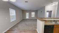 Located at 501 Tiger Way in Knoxville, Tennessee, this one-bedroom, one-bathroom single-floor unit offers a functional and well-appointed layout. The open-concept living and dining area is bright and welcoming, featuring plush carpet flooring, neutral gray walls, and multiple windows that bring in natural light. A glass-paned door provides direct outdoor access from the living room, enhancing the sense of openness.

The kitchen is positioned adjacent to the living area and is defined by a granite-topped breakfast bar peninsula. Warm honey-toned cabinetry provides ample storage, while black appliances — including a refrigerator, range, and built-in microwave — complete the space. A pendant light fixture above the entry area adds a decorative touch.

The bedroom is a comfortable size, carpeted, and equipped with a ceiling fan. It includes a closet and connects to the full bathroom, which features a granite-topped vanity with wood cabinetry, a tub-shower combination with white tile surround, and wood-look vinyl flooring.

A dedicated laundry area accommodates a full-size washer and dryer with overhead wire shelving for additional storage. Throughout the unit, clean white trim, consistent neutral tones, and practical finishes create a cohesive and move-in-ready living environment.
