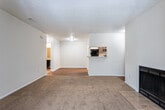 Located at 100 Knight Way in Fayetteville, Georgia, this single-floor residence offers a practical and comfortable layout with a variety of functional living spaces. The living area is a welcoming focal point, featuring plush carpeting, a wood-burning fireplace with a tiled hearth, and a pass-through window that connects to the kitchen, creating an open and interactive feel between the spaces. Natural light filters in through multiple windows throughout the home, enhancing the bright, neutral color palette found in every room. The kitchen is well-appointed with dark cabinetry, a double stainless steel sink, and light granite-style countertops that provide ample workspace. Rich hardwood flooring runs through transitional areas, adding warmth and character to the overall design. The bedrooms are generously sized, finished with soft carpet and multiple windows that invite natural light and views of the surrounding greenery. The bathroom features a wide vanity with granite-style countertops, a round undermount sink, dark cabinetry, and framed mirrors with accent lighting. Textured ceilings are consistent throughout the home, and closet storage is available in the bedroom areas. The space presents a clean, move-in-ready environment suitable for a range of lifestyles.