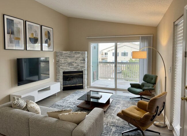 Amplia sala familiar con una hermosa chimenea revestida de piedra con vistas al balcón del apartamento. - 8427 Thunder Ridge Way #203