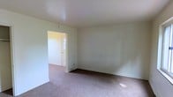 This three-floor property presents a straightforward and functional layout with a clean, understated aesthetic throughout. The interior features neutral, light-toned walls that create a bright and airy atmosphere, complemented by smooth ceilings and classic white trim and baseboards that frame each room with a crisp, tidy finish.

The main living area is generously proportioned, with soft wall-to-wall carpeting underfoot that adds warmth and comfort to the space. The room flows naturally toward a front entryway, where a paneled front door with glass detailing allows natural light to filter in, creating a welcoming transition between the interior and the outside. The open sightlines between rooms reinforce a sense of spaciousness and ease of movement throughout the floor.

The three-floor configuration provides ample separation of living spaces, offering flexibility for a variety of uses across the levels. The consistent use of neutral tones and clean finishes throughout lends the property a cohesive, move-in ready character. Overall, the space is defined by its simplicity, practicality, and light-filled rooms, making it a versatile and functional property well-suited to a range of occupants and lifestyles.