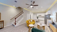 Located in Atascocita, TX, this well-appointed two-story home offers three bedrooms, three bathrooms, and a thoughtfully designed layout spread across two floors. The main level features an open-concept living, dining, and kitchen area bathed in recessed lighting and distinguished by striking LED-lit tray ceilings that add a warm, modern ambiance throughout. Light wood-look flooring flows seamlessly underfoot, while a classic white staircase with a rich wood banister serves as a stylish focal point. The kitchen is outfitted with crisp white shaker cabinets, granite countertops, a grey tile backsplash, stainless steel appliances, and an elegant marble-top dining table at its center. Upstairs, the spacious primary bedroom offers a ceiling fan, plush carpeting, and direct access to a beautifully finished en-suite bathroom featuring marble-look tile, a glass-enclosed shower, and a soaking tub. The additional bedrooms are cozy and well-sized, including one with charming decorative wall accents. Each of the three bathrooms is finished with quality materials throughout. Three dedicated closets provide ample storage. The home's consistent use of neutral tones, quality finishes, and modern lighting creates a cohesive, inviting atmosphere from entry to upper level.