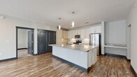 Located at 2107 Lothric Way in Murfreesboro, TN, this well-appointed 2-bedroom, 2-bathroom residence offers a thoughtfully designed single-floor layout with modern finishes throughout. The open-concept kitchen and living area serves as the heart of the home, anchored by a large central island topped with a stone countertop and flanked by sleek white cabinetry that extends to the ceiling. Stainless steel appliances, a subway tile backsplash, and stylish pendant lighting complete the contemporary kitchen aesthetic. Warm wood-look flooring flows throughout the main living areas, complemented by dark-trimmed doors and baseboards that add a bold contrast to the light-toned walls. The spacious living room receives generous natural light through large windows and provides direct access to a private balcony. Both bedrooms are carpeted and include ceiling fans and ample natural light. The primary bedroom features its own walk-in closet with wire shelving, while additional closets throughout the unit offer plentiful storage. The bathrooms are finished with large-format marble-look tile, including an elegant tub-shower surround. A dedicated hallway connects the living spaces to the private quarters, contributing to a well-organized and functional floor plan.