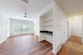 This single-floor space combines functional design with comfortable living across several well-defined areas. Rich hardwood flooring extends throughout the main living spaces, including the open-concept living room and kitchen areas, while plush carpeting adds warmth to the bedrooms.

The kitchen is outfitted with white shaker-style cabinetry, dark countertops, a subway tile backsplash, and a full suite of stainless steel appliances, including a refrigerator, range, and microwave. A peninsula with a dark countertop offers a convenient pass-through to the living area, where crown molding and a ceiling fan contribute to a polished finish. Large windows invite abundant natural light and outdoor views of surrounding greenery.

Adjacent to the living area is a nook featuring built-in shelving and a dark countertop, ideal for use as a workspace or display area. The bedrooms are generously sized, each featuring ceiling fans, multiple windows, and soft carpeted floors.

The bathrooms are clean and bright, with white tile surrounding a soaking tub and shower combination, accented by a neutral tile border. Hardwood flooring carries through to the secondary bathroom, maintaining visual continuity. Overall, the space presents a bright, cohesive aesthetic throughout.