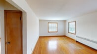 This two-bedroom, one-bathroom unit in Wauwatosa, Wisconsin is laid out entirely on a single floor, offering a straightforward and functional floor plan. Warm hardwood flooring flows consistently throughout the living areas and both bedrooms, complemented by wood-trimmed windows and matching baseboards that lend a cohesive, classic character to the space.

The living room is generously proportioned, featuring two windows that invite ample natural light and provide views of the surrounding exterior. A radiator unit provides heating, maintaining the home's traditional character. The second bedroom mirrors this setup with its own window and radiator, while the primary bedroom offers a slightly larger footprint with an additional window and access to a closet.

The kitchen is equipped with a white range and features light tile flooring, providing a practical workspace distinct from the hardwood areas. The full bathroom retains its vintage charm with pink wall tile surrounding the tub-shower combination, a mosaic tile floor in soft pastel tones, a white vanity, and a frosted window above the tub for natural light and privacy.

Overall, the unit presents a well-maintained, classic aesthetic with consistent warm-toned wood details and functional room layouts throughout.