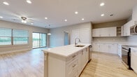 This single-floor space showcases a clean, contemporary design highlighted by light wood-style flooring and neutral warm-gray walls that carry consistently throughout. The open-concept kitchen serves as a central hub, anchored by a large white island with an undermount sink, white quartz countertops, and shaker-style cabinetry fitted with brushed nickel hardware. Stainless steel appliances, including a range, microwave, and refrigerator, complete the kitchen. Recessed lighting and a pendant fixture illuminate the space efficiently.

The living and dining area flows directly from the kitchen, offering generous room to move. A sliding glass door leads to a private balcony with outdoor views, while an additional window allows ample natural light. A ceiling fan provides additional comfort.

The bedrooms are well-sized, each featuring ceiling fans, large windows with exterior views, and walk-in closet space with wire shelving systems. The primary bathroom is notably spacious, with dual vanities featuring white quartz counters, shaker cabinets, and large-format marble-style tile flooring. A secondary bathroom mirrors the same refined aesthetic with a single vanity and marble-style tile. The overall ambiance is bright, clean, and move-in ready.