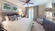 This single-floor residence offers a thoughtfully designed layout that balances comfort and functionality across its main living areas. The open-concept kitchen features warm honey-toned cabinetry, granite countertops, a tile backsplash, and stainless steel appliances, including a built-in microwave and range. A peninsula with bar seating and pendant lighting connects the kitchen to the dining area, which is illuminated by track lighting and provides ample space for a full dining table. The living room is generously proportioned, finished with plush carpet, a ceiling fan, and large windows dressed with drapes that invite natural light.

The primary bedroom is a serene retreat with carpeted flooring, a ceiling fan, access to an outdoor area through French doors, and an en-suite bathroom. The en-suite features warm wood cabinetry, granite countertops, a framed mirror with vanity lighting, and a shower-tub combination with decorative curtains. A second bedroom offers comfortable proportions, a closet, ceiling fan, and direct access to an additional full bathroom. Both bathrooms are finished with clean tile work and functional fixtures. Throughout the residence, neutral tones and consistent finishes create a cohesive and welcoming ambiance.