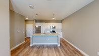 This 1-bedroom, 1-bathroom unit in Birmingham, AL offers a thoughtfully designed open-concept layout with modern finishes throughout. The kitchen serves as the centerpiece of the living area, anchored by a large island with granite countertops, an undermount sink, and pendant lighting overhead. White shaker-style cabinetry lines the walls, complemented by a subway tile backsplash and a full suite of stainless steel appliances, including a refrigerator, electric range, microwave, and dishwasher. Warm-toned wood-look flooring flows seamlessly through the main living areas, enhancing the bright, airy feel of the space. Natural light enters through a double-door entry and bedroom windows, providing pleasant outdoor views. The bedroom features plush carpet, a ceiling fan, a dedicated closet, and direct access to the full bathroom. The bathroom is finished with tile flooring, a granite-topped vanity, and a walk-in glass-enclosed shower with floor-to-ceiling white tile. A dedicated laundry room houses a full-size washer and dryer with overhead shelving for added storage. The unit combines practical functionality with clean, contemporary design throughout.