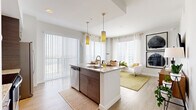 This thoughtfully designed 2-bedroom, 2-bathroom residence spans a single floor and features a clean, modern aesthetic throughout. The open-concept kitchen and living area serves as the heart of the home, where a sleek kitchen showcases dark wood cabinetry, subway tile backsplash, stainless steel appliances, and a granite-topped island with bar seating illuminated by stylish pendant lighting. Light wood-style flooring flows seamlessly into the living room, which is framed by floor-to-ceiling windows and a sliding glass door that fills the space with natural light and provides sweeping outdoor views of the surrounding cityscape. The primary bedroom is a comfortable retreat featuring plush carpeting, generous closet access, and a private en-suite bathroom with a granite vanity, dark wood cabinetry, and a tub-shower combination with classic white subway tile. The second bedroom mirrors this bright, airy character with large windows and soft carpeting. The second bathroom offers a consistent design language, featuring the same granite countertops and tiled tub-shower setup. A clean hallway connects the private areas of the residence, maintaining an efficient and intuitive layout. Neutral tones and modern finishes are carried consistently throughout, creating a cohesive and inviting atmosphere.