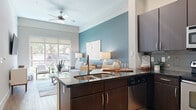 Located at 4100 Greenbriar Dr in Houston, TX, this thoughtfully designed one-bedroom, one-bathroom residence offers a smart and functional layout across a single floor. The open-concept kitchen and living area serves as the heart of the home, where rich dark-espresso cabinetry, dark granite countertops, a subway tile backsplash, and a full suite of stainless steel appliances make the kitchen both stylish and practical. A breakfast bar with seating provides a seamless transition into the living space, which is anchored by a bold teal accent wall, wood-look flooring, and expansive floor-to-ceiling windows that flood the room with natural light and offer lush outdoor views. The bedroom features plush carpeting, large windows, and a calming, neutral color palette that promotes rest. The bathroom is finished with dark wood vanity cabinetry, a full soaking tub with shower, and tile flooring. A dedicated office space adds versatility, while the in-unit laundry room with full-size washer and dryer adds everyday convenience. Four closets provide generous storage throughout. The overall ambiance is modern and welcoming, with a cohesive design that balances comfort and contemporary style.