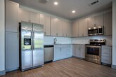 Located at 355 Walnut St in Chattanooga's vibrant Southside neighborhood, this single-floor unit offers a thoughtfully designed layout with contemporary finishes throughout. The open-concept living and kitchen area is anchored by light hardwood flooring, recessed lighting, and a ceiling fan, creating a bright and airy atmosphere. Large windows and a glass-paned door in the living area invite abundant natural light and provide access to an outdoor balcony with views of surrounding greenery.

The well-appointed kitchen features gray shaker-style cabinetry extending to the ceiling for ample storage, granite countertops, a white subway tile backsplash, and a full suite of stainless steel appliances including a French door refrigerator, range, microwave, and dishwasher.

A wide hallway connects the living spaces to the private quarters. Bedrooms are carpeted for comfort, each equipped with a ceiling fan and closet. One bedroom features a walk-in closet. Two full bathrooms serve the unit — one with a tiled walk-in shower and granite vanity, the other with a tiled soaking tub/shower combination and matching granite vanity with gray cabinetry. Clean white walls and consistent finishes throughout lend the space a cohesive, modern character.
