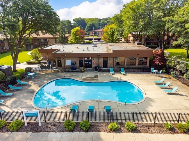 Heated pool equipped with comfy lounge chairs at Westwood Village Apartments in Westland, MI - Westwood Village Apartments