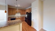Located at 1334 Blue Sky Dr NW in Concord, North Carolina, this single-floor home offers a practical and cohesive layout designed for comfortable everyday living. The kitchen serves as a functional centerpiece, equipped with warm honey-toned wood cabinetry, granite-style countertops, a peninsula that provides additional prep space, and a full suite of black appliances including a refrigerator, electric range, over-the-range microwave, and dishwasher. Track lighting and a pendant light add focused illumination throughout the space. Hardwood-style flooring runs through the kitchen, transitioning to plush carpeting in the bedrooms.

The bedrooms are finished with neutral walls and feature windows with blinds that allow natural light. The primary bedroom includes direct access to a dedicated closet and a private bathroom with a walk-in shower. A second full bathroom contains a soaking tub with a shower combination and brushed nickel fixtures. A dedicated in-unit laundry area accommodates a full-size washer and dryer with an overhead shelf for additional storage. Throughout the home, clean white trim and warm neutral tones create a consistent, understated aesthetic.