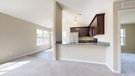 Located at 463 Timber Pointe Dr in Joliet, IL, this single-floor home features an open-concept layout with vaulted ceilings that lend a sense of generous vertical space throughout the main living areas. The kitchen is a functional centerpiece, equipped with rich dark cabinetry, granite countertops, and a full suite of stainless steel appliances including a gas range, built-in microwave, and refrigerator. A peninsula-style breakfast bar connects the kitchen to the adjoining living and dining areas, creating a cohesive flow ideal for everyday living and entertaining.

The dining area receives an abundance of natural light through large windows and a sliding glass door that opens onto a deck overlooking a scenic outdoor view with mature trees and water. Soft carpeting covers the spacious living and bedroom areas, while light hardwood-style flooring is found in the kitchen and dining spaces. The bedrooms are well-proportioned with large windows that invite natural light and outdoor views. A bathroom includes a full tub-shower combination with chrome fixtures and light wood-tone flooring. Neutral warm-beige tones throughout create a clean, welcoming ambiance.