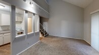 Located at 2722 S Topeka St in Wichita, Kansas, this two-story, one-bedroom, one-bathroom residence offers a well-organized layout spread across two levels. The main floor houses the living room, kitchen, and bathroom, while the upper level contains the bedroom and an additional loft-style space.

The living room is an immediate standout, featuring dramatically vaulted ceilings that create a strong sense of height and openness. Soft carpet covers the floor throughout the living areas, and a sliding glass door fitted with vertical blinds allows natural light to fill the space. A staircase with a metal railing connects the main level to the upper floor.

The kitchen is positioned adjacent to the living room in an open-concept arrangement, visible through a pass-through opening. It is outfitted with white cabinetry, laminate countertops, a double-basin sink, and white appliances including a refrigerator, dishwasher, and a coil-burner electric range. Wood-look flooring runs throughout the kitchen area.

Upstairs, the bedroom features carpeted floors, a window for natural light, and a mirrored sliding-door closet. A loft area adjacent to the bedroom offers additional flexible space with angled walls and high windows. The bathroom includes a full tub-shower combination with built-in shelving and chrome fixtures.