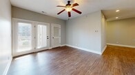 Located at 120 Portico St in Lynchburg, Virginia, this well-appointed single-floor home offers three bedrooms, two full bathrooms, and a thoughtfully designed layout. The open-concept living area seamlessly integrates the living room, dining room, and kitchen, creating a bright and connected space. The kitchen is equipped with stainless steel appliances, rich dark wood cabinetry, granite countertops, and a breakfast bar with pendant lighting — an ideal setup for both everyday living and entertaining. Wood-look flooring flows throughout the main living areas, while ceiling fans add comfort to the living room and bedrooms. The living room opens to a private balcony through French doors, bringing in abundant natural light. The bedrooms are carpeted and generously sized, with the primary bedroom offering ample space and access to a walk-in closet with wire shelving. Both bathrooms feature dark cabinetry with granite countertops and tub/shower combinations with oil-rubbed bronze fixtures. A dedicated in-unit laundry area accommodates a full-size washer and dryer. Additional highlights include a pantry, a utility room, and four closets total, ensuring excellent storage throughout. Neutral gray walls and clean white trim give the home a modern, move-in-ready aesthetic.