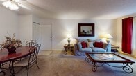 This single-floor residence in Hanahan, South Carolina offers a well-organized layout designed for comfortable everyday living. The living room serves as the heart of the home, featuring plush carpeted flooring, a large sliding glass door with vertical blinds that draws in natural light, and ample space for seating and entertaining. A dedicated dining area adjacent to the living space includes a ceiling fan with light fixture and a built-in wall niche, adding a subtle architectural detail to the room. The galley-style kitchen is outfitted with warm wood cabinetry, light countertops, tile flooring, and full-size appliances including a refrigerator and range. The primary bedroom offers carpeted floors, a closet, and a window, providing a quiet and private retreat. A secondary bedroom mirrors this comfort with soft carpet, natural light from a window, and a closet. Both bathrooms feature tile flooring and vanities with wood cabinetry; one includes a shower-tub combination. Throughout the residence, neutral wall tones and consistent finishes create a cohesive and inviting atmosphere suited to a variety of lifestyles.
