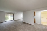 Located at 5915 Griffin Dr in Cicero, NY, this two-bedroom, one-bathroom residence offers a well-organized single-floor layout with a clean, neutral aesthetic throughout. The expansive open-plan living and dining area is carpeted in neutral tones and bathed in natural light from large windows and a sliding glass door that opens to a private balcony with outdoor views. A wall-mounted mini-split unit provides climate control, complemented by baseboard heating along the perimeter walls. The kitchen is thoughtfully designed with warm wood cabinetry, white countertops, a stainless steel range, a dishwasher, and a peninsula that opens toward the dining area — ideal for everyday functionality. Both bedrooms are carpeted and feature white panel closet doors, with the primary bedroom offering a generous footprint and ample closet space. In total, four closets are distributed throughout the unit, providing excellent storage. The full bathroom includes a tiled tub-shower combination with a grab bar and clean white fixtures. The overall ambiance is bright, clean, and move-in ready, with a straightforward layout that maximizes usable space throughout.