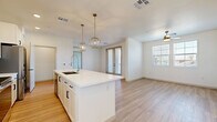 Located at 4353 E Elliot Rd in Gilbert, AZ, this well-appointed 2-bedroom, 2-bathroom single-story home offers a clean, modern aesthetic with thoughtful design throughout. The open-concept kitchen and living area serves as the heart of the home, anchored by a central island with a crisp white quartz countertop, an integrated sink with a gooseneck faucet, and stylish gold geometric pendant lights. The kitchen features white shaker cabinetry extending to the ceiling, a subtle tile backsplash, and stainless steel appliances including a French door refrigerator, range, and microwave. Light wood-look flooring runs through the main living areas, complementing the bright, neutral color palette. The living area benefits from natural light through windows and French doors, with a ceiling fan adding comfort. The primary bedroom offers generous space with light wood flooring, a ceiling fan, and a walk-in closet featuring built-in shelving and carpet underfoot. The second bedroom is carpeted and well-lit with multiple windows. Both bedrooms share access to two full bathrooms, one of which includes a tiled soaking tub and shower combination. A dedicated laundry area with an included washer rounds out this efficiently designed home.