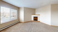 Located at 24905 CR-75 in St. Augusta, MN, this single-floor, one-bedroom, one-bathroom unit offers a thoughtfully laid-out living space with functional design throughout. The living room is a welcoming area featuring plush carpeting, a baseboard heating system, a large window that brings in natural light with outdoor views, and a corner fireplace that serves as a warm focal point. Adjacent to the living room, the kitchen is well-appointed with ample warm-toned wood cabinetry, dark countertops, tile flooring, and a full suite of white appliances including a refrigerator, range, microwave, and dishwasher. A convenient breakfast bar connects the kitchen to the living area. The bedroom is a generously sized, carpeted retreat with a wide window offering outdoor views and a dedicated walk-in closet for added storage. The bathroom is spacious and includes a combination tub and shower, a large vanity with warm wood cabinetry, a wide mirror with overhead lighting, and tile flooring. A standout feature is the in-unit stacked washer and dryer, conveniently located within the bathroom. Neutral tones, wood-trimmed doors, and consistent finishes throughout lend the space a cohesive and comfortable character.
