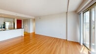 Located at 295 Harvard St in Cambridge's vibrant Cambridgeport neighborhood, this two-bedroom, two-bathroom residence offers a well-designed single-floor layout with a clean, modern aesthetic throughout. The open-concept kitchen and living area serves as the heart of the home, featuring a large granite-topped peninsula with an integrated sink, white cabinetry, dark countertops, and a full suite of stainless steel appliances including a refrigerator, range, and microwave. Recessed lighting illuminates the kitchen, which flows seamlessly into the spacious living area. The living room is bathed in natural light through large sliding glass doors that open to a balcony with sweeping views of the Cambridge and Boston skyline — a standout feature of the space. Warm hardwood flooring extends throughout the living areas and bedrooms, complementing the bright white walls. The generously sized primary bedroom includes an en-suite bathroom, while a second full bathroom serves the additional bedroom and guests. Both bathrooms feature tile flooring, white vanities, and modern fixtures. The secondary bedroom offers a window with neighborhood views and ample space. A dedicated closet provides convenient storage. The overall ambiance is bright, clean, and contemporary, well-suited for comfortable urban living.