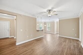 This 1,130-square-foot single-floor residence offers a thoughtfully designed 2-bedroom, 2-bathroom layout with a seamless blend of comfort and functionality. The open-concept kitchen and living area serves as the heart of the home, featuring rich warm-toned wood cabinetry, granite countertops, stainless steel appliances, a breakfast bar with pendant lighting, and light hardwood-style flooring that extends throughout the main living areas. Crown molding and ceiling fans add a polished finish to the living room, which also benefits from natural light through window treatments. The galley-style kitchen provides generous cabinet storage and ample counter space. Both bedrooms are carpeted and well-lit, each equipped with a ceiling fan and multiple windows with blinds. The primary bedroom measures 170 square feet and offers comfortable proportions. The two bathrooms feature hardwood-style flooring, warm wood vanities with granite countertops, and large mirrors; one includes a tub/shower combo. A dedicated laundry room houses a full-size washer and dryer with overhead cabinetry for added storage. Three closets throughout the unit further enhance storage capacity. Two hallways connect the spaces efficiently within the single-floor floorplan.