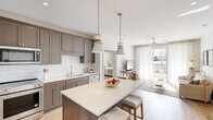 This well-appointed two-bedroom, two-bathroom residence on Village Green Blvd in Aiken, SC offers a comfortable and modern single-floor layout. The open-concept kitchen is a standout feature, showcasing warm taupe shaker-style cabinetry, a classic white subway tile backsplash, quartz countertops, stainless steel appliances, and a central island with seating — all illuminated by elegant pendant lighting. The kitchen flows seamlessly into the bright living room, which is anchored by a ceiling fan, recessed lighting, and a sliding glass door framed by sheer white curtains that invite natural light and provide direct access to an outdoor view. The primary bedroom is a serene retreat of generous size, while the second bedroom offers cozy, well-proportioned accommodations with warm carpet flooring. Both bathrooms are finished with large-format marble-style tile floors. The primary bath features an extended dual-sink vanity with ample cabinetry, a glass-enclosed shower, and direct access to a walk-in closet. The second bathroom includes a single vanity, a soaking tub, and an adjacent closet. Throughout the residence, a neutral color palette and consistent finishes create a cohesive, move-in-ready aesthetic.