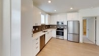 Located at The Inlet, this thoughtfully designed single-floor residence offers a clean, contemporary aesthetic with an open and airy feel throughout. The open-concept living and kitchen area is anchored by light-toned hardwood flooring that extends seamlessly across the space, while recessed lighting and multiple windows invite an abundance of natural light.

The kitchen is a standout feature, boasting crisp white cabinetry extending to the ceiling for generous storage, a warm earth-toned tile backsplash, light countertops, and a full suite of stainless steel appliances including a refrigerator, range, microwave, and dishwasher. The layout flows naturally into the living area, which includes access to an exterior door and a window that frames outdoor views.

The bedrooms are carpeted for comfort and feature ceiling fans, ample natural light through horizontal-blind-fitted windows, and neutral wall tones that create a calm, restful atmosphere. One bedroom is served by a spacious walk-in closet outfitted with multi-level wire shelving systems, providing extensive organization options.

The bathroom is finished in clean white tones, featuring a full soaking tub with shower combination and polished chrome fixtures. Every element of this residence reflects a modern, functional design sensibility suited for comfortable everyday living.