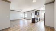 Located at 4651 S Custer Rd in McKinney, TX, this well-appointed 3-bedroom, 2-bathroom residence offers a thoughtfully designed single-floor layout with generous living space throughout. A welcoming entrance hallway with wood-look flooring leads into an expansive open-concept living, dining, and kitchen area filled with natural light from multiple windows. The kitchen is outfitted with dark espresso cabinetry, granite countertops, stainless steel appliances including a refrigerator and dishwasher, and a breakfast bar, complemented by a pantry for additional storage. The living area features a ceiling fan and seamlessly extends to a private balcony. The primary bedroom includes wood-look flooring, a ceiling fan, crown molding accents, and a natural light-filled window. The two additional bedrooms are carpeted, each with ceiling fans and windows offering outdoor views. Both bathrooms feature granite-topped dark wood vanities, large mirrors, and wood-look flooring. The dedicated laundry room includes a full-size washer and dryer. Five closets provide abundant storage throughout. A utility room and hallway complete the practical, well-organized floor plan, making this residence a comfortable and functional home.