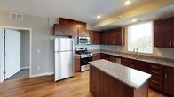 This single-floor residence offers a thoughtfully designed layout that balances functionality with modern finishes. The kitchen serves as a standout feature, showcasing rich dark-wood cabinetry, granite countertops, stainless steel appliances including a gas range, built-in microwave, refrigerator, and dishwasher, along with a central island that adds prep space and a natural gathering point. Warm hardwood-style flooring runs throughout the kitchen and open living areas, creating a cohesive and inviting atmosphere.

The open living and dining area features neutral grey walls, clean white trim, and a layout that allows for flexible furniture arrangements. Natural light filters in through multiple windows fitted with horizontal blinds, offering views of surrounding greenery.

Multiple bedrooms are finished with plush neutral-toned carpet, subdued warm wall colors, and generous windows that bring in natural light and outdoor views. Each bedroom provides a calm, versatile space. Closet access is present in select rooms.

Two full bathrooms mirror each other in design, each featuring a soaking tub with shower combination, a dark-wood vanity with white countertop and integrated sink, and light tile flooring. The overall aesthetic throughout the residence is clean, contemporary, and move-in ready.