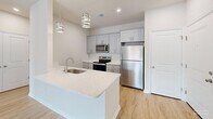 Located at 2897 Easton Ave in Bethlehem, PA, this thoughtfully designed single-floor residence offers a bright and contemporary living experience. The open-concept kitchen and living area serves as the heart of the home, showcasing a sleek island with a quartz countertop and undermount sink, gray shaker-style cabinetry, stainless steel appliances including a refrigerator, electric range, and microwave, and elegant pendant lighting overhead. The living area flows seamlessly from the kitchen and features light wood-look flooring, a ceiling fan, and sliding glass doors that open to a private balcony with outdoor views. The spacious primary bedroom provides a generous and serene retreat, complemented by clean neutral walls and the same warm flooring found throughout. A versatile den offers additional flexible space, ideal for a home office or secondary lounge. The full bathroom includes a soaking tub and shower combination with brushed nickel fixtures and recessed lighting. A dedicated hallway and closet provide practical storage solutions. Natural light fills the unit through multiple windows fitted with blinds, contributing to an airy and inviting ambiance throughout.