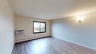 Located at 2815 Elisha Ave in Zion, IL, this one-bedroom, one-bathroom unit offers a practical and comfortable layout across a single floor. The entrance opens into a well-connected interior with light-toned walls and textured ceilings throughout. The combined dining and living area is bright and open, featuring durable hardwood-style flooring and a wall-mounted A/C unit, with natural light streaming in through sliding windows that offer outdoor views of the surrounding neighborhood and greenery. The kitchen includes a ceiling fan, a full-size refrigerator, and a closet pantry for added storage. The bedroom is comfortably sized with plush carpeting, a built-in double closet, and a window that lets in natural light. Additional closets throughout the unit provide generous storage options. The bathroom features a full tub and shower combination with classic tile surround in a warm cream tone, chrome grab bars, and a built-in soap dish. Baseboard heating runs throughout the unit, ensuring consistent warmth. Clean, neutral finishes and a well-organized floor plan make this a functional and move-in-ready space in Zion, Illinois.