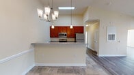 Located in Wake Forest, NC, this single-floor residence offers a thoughtfully designed open-concept layout that blends comfort and functionality. The kitchen is a standout feature, showcasing rich cherry wood cabinetry, granite countertops, and a full suite of stainless steel appliances including a refrigerator, range, and microwave. A peninsula breakfast bar with pendant lighting separates the kitchen from the dining area, while a skylight above floods the space with natural light. Soaring vaulted ceilings amplify the sense of openness throughout the kitchen and dining areas.

The spacious living room features warm wood-look flooring, a ceiling fan, and French doors flanked by large windows that invite abundant natural light and provide views of the surrounding neighborhood. The bedrooms are generously sized, with wood-look flooring, large windows with blinds, and arched interior doors. The bathrooms are finished with granite-topped vanities, cherry wood cabinetry, and tile flooring. One bathroom includes accessibility-friendly grab bars. Throughout the home, neutral warm tones, clean white trim, and consistent finishes create a cohesive and welcoming ambiance.