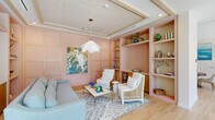 Located at 125 Quadrille Plaza Dr in West Palm Beach, Florida, this thoughtfully designed single-floor space offers a generous layout across multiple rooms, combining sophistication with a warm, coastal aesthetic. The entrance welcomes visitors with floor-to-ceiling windows that flood the space with natural light and provide views of lush exterior landscaping. Light hardwood flooring flows seamlessly throughout, creating a cohesive and airy atmosphere.

The lounge area is a standout feature, showcasing blush pink paneled walls, a textured tray ceiling, built-in shelving, and a petal-shaped pendant light. Vibrant botanical artwork and cane-accented seating lend a refined, Florida-inspired charm to the space.

A glass-partitioned private office offers transparency and openness while maintaining functionality, furnished with natural wood cabinetry and patterned carpeting. Adjacent to it, a conference area features a substantial solid wood table, built-in cabinetry, and nautical artwork, with exterior views adding to the bright ambiance.

A mail and lounge area is elegantly appointed with a round wood table, upholstered seating, ornate gold pendant fixtures, and dual rows of individual mailboxes framed by coastal landscape paintings. A full bathroom completes the layout. Together, these spaces form a polished, welcoming environment ideal for professional or community use.