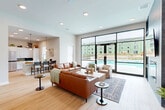 Located at 1000 Autumn Hollow Cir in Wentzville, MO, this thoughtfully designed single-floor amenity space offers a generous and versatile layout for residents and guests alike. Light-toned hardwood flooring runs throughout, complementing the clean white walls and recessed lighting that give the space a bright, contemporary feel.

The expansive great room serves as the heart of the facility, anchored by a floor-to-ceiling glass wall that opens directly to an outdoor pool area, flooding the interior with natural light and providing seamless indoor-outdoor connectivity. A tile-surround fireplace with a wall-mounted TV anchors one side of the room, while comfortable seating arrangements invite relaxation and socializing.

The adjacent kitchen is well-appointed with white shaker cabinetry, a decorative patterned tile backsplash, stainless steel appliances, and ample counter space — ideal for community gatherings. Two private office rooms offer intimate settings for focused work or small meetings, each furnished with round tables and modern seating.

The dedicated gym is fully equipped with cardio machines, a cable weight system, free weights, resistance tools, and exercise balls, all set on durable flooring with mirror walls and natural light from surrounding windows. A welcoming entrance and hallway complete this functional and stylish community space.