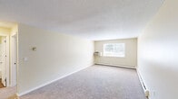 Located at 59 Mill Pond Rd in Broad Brook, CT, this single-floor, 2-bedroom, 1-bathroom residence offers a functional and well-organized layout. The living room is notably spacious, featuring neutral beige walls, plush wall-to-wall carpeting, a textured ceiling, and a wall-mounted air conditioning unit. Natural light filters in through a window overlooking the outdoors, complemented by baseboard heating along the perimeter. The transition between the living area and the rest of the unit is marked by a shift to durable wood-look flooring, which continues through the kitchen and bathroom. The galley-style kitchen is efficiently designed with light wood cabinetry, granite-look countertops, a stainless steel refrigerator, stove, and a double sink. Both bedrooms are carpeted and bathed in natural light, with the spacious primary bedroom offering a generous walk-in closet equipped with a full-width hanging rod. The full bathroom includes a tub/shower combination with built-in shelving, a white vanity, and wood-look flooring. Throughout the unit, the clean, neutral palette and consistent finishes create a cohesive and move-in-ready living environment.