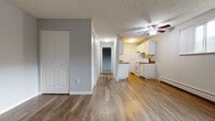 This single-floor unit offers a practical and comfortable layout with a clean, neutral design throughout. The open living and dining area is finished with durable wood-look vinyl flooring and features a ceiling fan, baseboard heating, and a wide window that invites natural light and views of surrounding greenery. The textured ceiling adds a classic touch consistent throughout the space.

The galley-style kitchen is efficiently designed with white cabinetry, dark laminate countertops, a double stainless steel sink, and white appliances including an electric range and refrigerator. Upper and lower cabinets provide ample storage, and the kitchen opens conveniently toward the main living area.

A hallway connects the living spaces to the private areas of the unit. The bedrooms feature plush carpeting, soft grey walls, and generous closet space — one room includes a mirrored sliding-door closet, while the other benefits from a window overlooking lush outdoor foliage. Baseboard heaters are present in both rooms for individual climate comfort.

The bathroom is well-appointed with white cabinetry, a stone-toned countertop vanity, an oval sink, and a large mirror. The wood-look flooring extends into the bathroom, maintaining a cohesive aesthetic. Overall, the space presents a functional, move-in-ready layout with consistent finishes throughout.