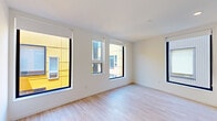 This thoughtfully designed 1-bedroom, 1-bathroom unit offers a clean, contemporary aesthetic throughout its single floor. Light-toned hardwood flooring flows seamlessly across every room, creating a sense of cohesion and warmth against the crisp white walls and ceilings.

The kitchen is a standout feature, outfitted with sleek white flat-front cabinetry extending to the ceiling for maximum storage, a vibrant cobalt blue penny-tile backsplash, stainless steel appliances including a gas range, built-in microwave, dishwasher, and refrigerator, as well as a wall-mounted mini-split HVAC unit. A large black-framed window fills the space with natural light.

The bedroom is a well-proportioned retreat with multiple large black-framed windows offering urban views, allowing generous natural light throughout the day. A wall-mounted mini-split unit ensures year-round climate comfort.

The bathroom is finished in a clean, minimalist style with a white undermount sink set in a white quartz vanity, modern chrome fixtures, and a large frameless mirror. The hallway connects all areas efficiently, maintaining an open and airy flow.

The unit's modern design, quality finishes, and abundant natural light make it a polished and functional living space.