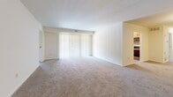Located at 101 Kenilworth Park Dr in Towson, MD, this single-floor unit offers three bedrooms, two bathrooms, a living room, and a kitchen across a comfortable and functional floor plan. The living room is generously proportioned, featuring plush carpeting, neutral cream walls, and a large sliding glass door fitted with vertical blinds that allows abundant natural light to fill the space. The kitchen is outfitted with light wood cabinetry, granite-style countertops, stainless steel appliances including a refrigerator, range, and microwave, and easy-to-maintain hardwood-style flooring. An adjoining dining or flex area benefits from additional windows and connects seamlessly to the rest of the unit. The spacious primary bedroom features dual windows that bring in ample natural light and is finished with soft wall-to-wall carpeting. The two additional bedrooms are similarly appointed with carpet flooring and windows providing natural light. Both bathrooms are finished with stone-look tile flooring, warm wood vanities with white countertops, mirrored medicine cabinets, and brushed nickel fixtures. A dedicated closet provides additional storage. The unit presents a clean, well-maintained interior with a consistent neutral palette throughout.