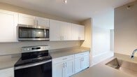 Located at 1101 Iroquois Ave in Naperville, IL, this single-floor residence offers a well-designed layout that balances functionality and comfort. The kitchen is a standout feature, outfitted with crisp white shaker-style cabinetry, gray quartz countertops, and a full suite of stainless steel appliances including an electric range, over-the-range microwave, and refrigerator. Wood-look flooring throughout the kitchen adds warmth and durability, while recessed and track lighting ensures excellent illumination. The open layout connects the kitchen seamlessly to the living area, which is finished with neutral-toned carpet and neutral wall colors that create a calm, inviting atmosphere. A notably spacious bedroom showcases a charming bay window that frames views of surrounding greenery, flooding the room with natural light. An additional bedroom features a single window with a garden view and baseboard heating. A hallway leads to a well-appointed full bathroom, complete with tile flooring, a soaking tub with tile surround, and a separate glass-enclosed shower. Throughout the unit, clean lines, neutral tones, and practical finishes come together to create a cohesive, move-in-ready living space.