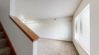 Located at 5201 SW 34th St in Topeka, Kansas, this two-story residence offers three bedrooms and two full bathrooms thoughtfully distributed across two floors. The main level features a functional kitchen equipped with oak-accented cabinetry, a double stainless steel sink, a dishwasher, and a range, all complemented by durable hardwood-style flooring and a window that brings in natural light. A carpeted living area on this floor provides a comfortable gathering space with access to a staircase leading to the upper level. Both bathrooms are clean and practical — one featuring a vanity with a framed mirror, and the other a full tub-shower combination. The upper floor houses the generously sized primary bedroom, which boasts mirrored sliding closet doors, a ceiling fan, and a window overlooking the exterior. Two additional bedrooms on the upper level also feature ceiling fans and plush carpet, providing comfortable and versatile spaces. Throughout the home, warm wood-toned door and window trim adds consistency to the neutral color palette. Textured ceilings are present throughout, and multiple windows ensure natural light reaches each room. A dedicated closet and hallway contribute to the home's functional layout, while the second kitchen adds a unique level of versatility to the space.