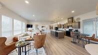 Located at 4719 W Garden Springs Rd in Spokane, WA, this thoughtfully designed single-floor community space offers a generous and versatile layout across its expansive footprint. The welcoming entryway greets visitors with light wood-look flooring, large glass double doors, and a comfortable seating area adorned with warm leather accent chairs and contemporary artwork, setting an inviting tone throughout.

The open-concept kitchen, dining, and living area forms the heart of the space. Rich dark-toned cabinetry, granite countertops, a large central island with bar seating, and black gas appliances give the kitchen a polished, functional character. Recessed lighting and pendant fixtures illuminate the space, while a wall-mounted TV and ample lounge seating make the living area ideal for gathering. Large windows and sliding glass doors flood the area with natural light and provide views of the surrounding outdoors.

The fitness center features soaring vaulted ceilings, rubber flooring, an expansive glass garage door for ventilation, and a full array of equipment including cardio machines, free weights, medicine balls, and dual wall-mounted TVs.

An additional multi-use room with high ceilings, a ceiling-mounted projector, and a golf simulator turf area serves as a flexible recreational and lounge space, complete with seating and ample natural light from large windows.