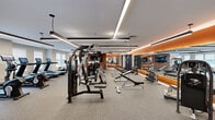 Discover the pinnacle of personal wellness in this extraordinary 1,670 square foot fitness center, meticulously designed to inspire and elevate your fitness journey. As you step into this light-filled space, you're greeted by an impressive array of top-of-the-line equipment, promising endless possibilities for your workout regimen.

The thoughtfully planned layout maximizes every inch, creating distinct zones for cardio, strength training, and functional fitness. Floor-to-ceiling windows flood the space with natural light, while sleek lighting fixtures add a touch of modern sophistication. The vibrant orange accents energize the environment, inspiring motivation and drive.

For cardio enthusiasts, a row of state-of-the-art treadmills, ellipticals, and stationary bikes await, each equipped with personal entertainment screens to make your workouts fly by. The strength training area boasts an extensive selection of free weights and resistance machines, catering to beginners and seasoned lifters alike.

A dedicated functional fitness zone features versatile equipment for dynamic, full-body workouts. The space's openness allows for group classes or personal training sessions, fostering a sense of community and support.

Attention to detail is evident throughout, from the premium flooring designed for comfort and safety to the stylish storage solutions keeping the space tidy and organized. The facility's modern aesthetic, with its clean lines and contemporary design, creates an atmosphere of luxury and motivation.

This isn't just a gym; it's a lifestyle upgrade, offering the convenience of a high-end fitness club in the comfort of your own property. Embrace the opportunity to prioritize your health and wellness, and unlock your full potential in this exceptional fitness haven.