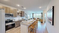 Located at 211 Hammond Center Dr in Raleigh, NC, this one-bedroom, one-bathroom residence offers a thoughtfully designed open-concept layout across a single floor. The kitchen serves as a central highlight, featuring warm wood-toned cabinetry, a classic white subway tile backsplash, granite countertops, stainless steel appliances, and a spacious island with bar seating — ideal for both casual dining and entertaining. The kitchen flows seamlessly into the living room, which is bathed in natural light from large windows and anchored by a ceiling fan. Light-toned hardwood-style flooring runs throughout, lending a cohesive and airy feel to the entire space. The bedroom is a comfortable retreat, highlighted by a large window with outdoor views, a ceiling fan, and direct access to the bathroom. The bathroom features a granite-topped double vanity with wood cabinetry, a large mirror, and a walk-in shower, connecting conveniently to the bedroom. A dedicated laundry area houses a full-sized stacked washer and dryer unit, adding practical convenience. The overall ambiance is modern and welcoming, with clean lines, neutral tones, and quality finishes throughout.