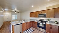 Located at 7355 N Willow Ave in Fresno, CA, this well-appointed single-story, one-bedroom, one-bathroom home offers a thoughtfully designed layout across a comfortable footprint. The open-concept living, dining, and kitchen area serves as the heart of the home, featuring warm wood-tone cabinetry, granite countertops, a peninsula with a sink, and a full suite of stainless steel appliances including a range, microwave, dishwasher, and refrigerator. Recessed lighting and a ceiling fan complement the space, while durable wood-look flooring flows throughout the main living areas. The living room is bright and welcoming, with a ceiling fan, crown molding, and a large window with vertical blinds that allow natural light to filter in. A hallway connects the main living area to the private bedroom, which features plush carpeting, a ceiling fan, and an outdoor-facing window. The home includes generous closet storage, a dedicated laundry area with a full-size washer and dryer, a pantry, and a patio for outdoor enjoyment. An attached garage provides convenient covered parking and additional storage. Crown molding and clean, neutral finishes throughout lend the home a polished, move-in-ready feel.